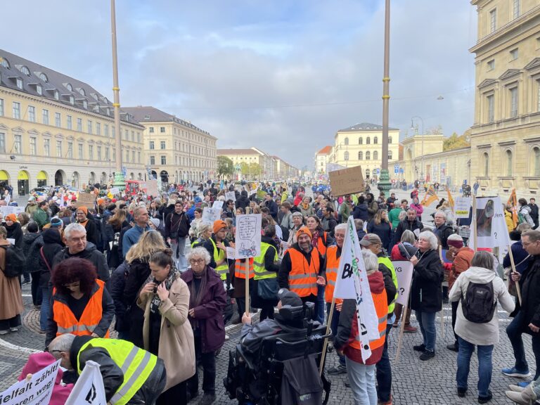 Blick ond er Feldhernnhalle in München auf eine Menschenmenge mit Schildern. Einige Personen haben Warnwesten an. Im Hintergrund sieht man die Ludwigstraße